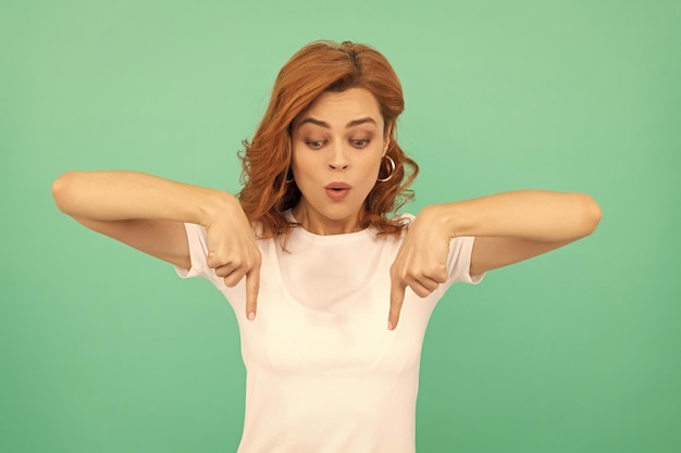 Donna sorpresa con i capelli ricci che puntano le dita verso il basso guarda la modella femminile