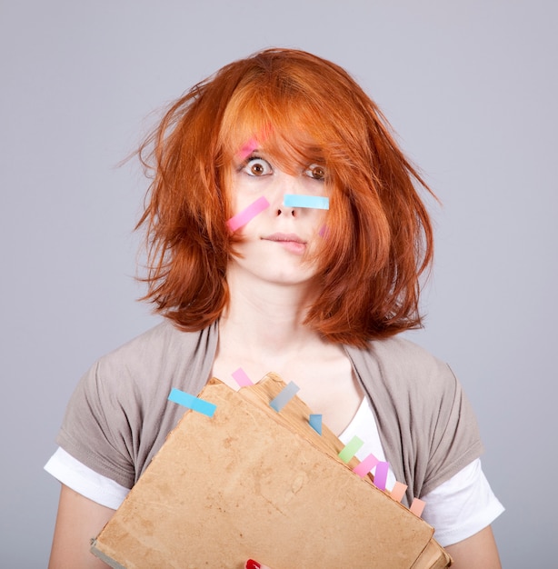 Donna sorpresa rossa con libro e note sul viso.