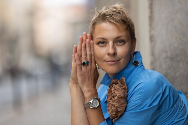 Donna sorridente alla moda adulta con i capelli corti che si siede sulla strada europea