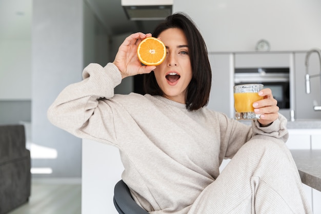 donna sorridente anni '30 che beve succo d'arancia, mentre riposa nella luminosa sala moderna