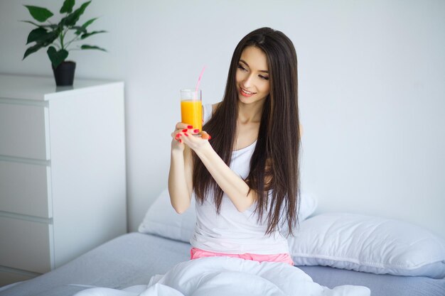 Donna sorridente casuale che tiene un bicchiere di succo d'arancia