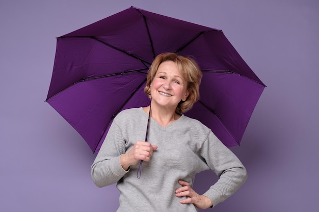 Donna sorridente caucasica senior con l'ombrello pronto per la pioggia