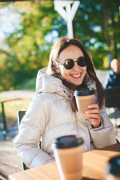 Donna sorridente che beve caffè nella caffetteria all'aperto