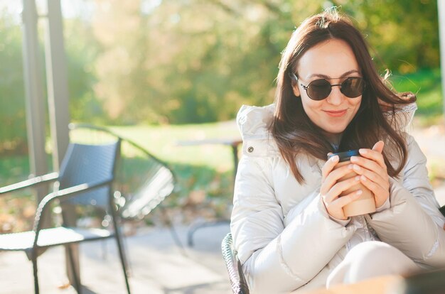 Donna sorridente che beve caffè nella caffetteria all'aperto