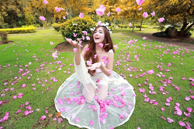 Donna sorridente che cattura fiori rosa mentre è seduta sull'erba