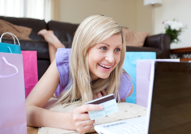 Donna sorridente che compera online che si trova sul pavimento