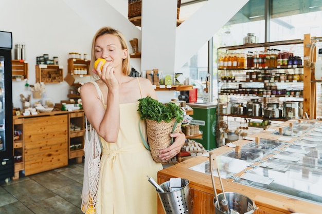 Donna sorridente che compra cibo biologico e prodotti ecologici in un negozio sostenibile privo di plastica