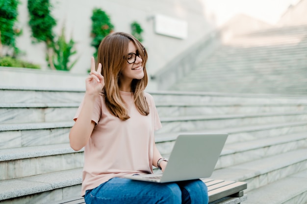 Donna sorridente che comunica via il computer portatile online all'aperto