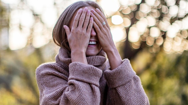 Donna sorridente che copre gli occhi al parco