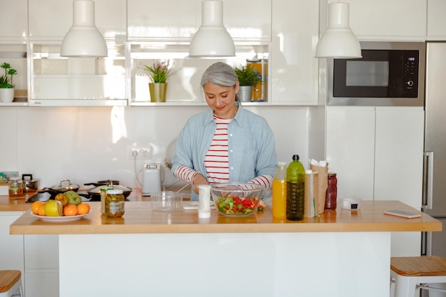 Donna sorridente che fa insalata fresca in cucina a casa