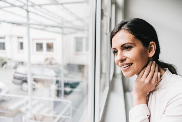 Donna sorridente che guarda fuori dalla finestra