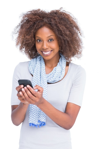 Donna sorridente che guarda l&#39;obbiettivo e digitando un messaggio di testo