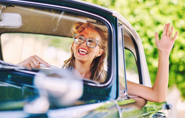 Donna sorridente che guida un'auto d'epoca