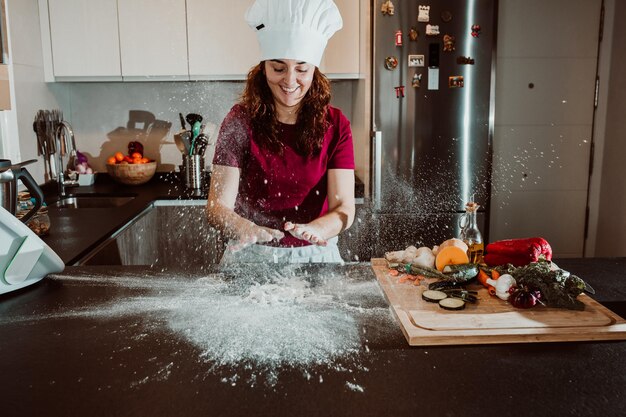 Donna sorridente che impasta la pasta sul bancone della cucina a casa