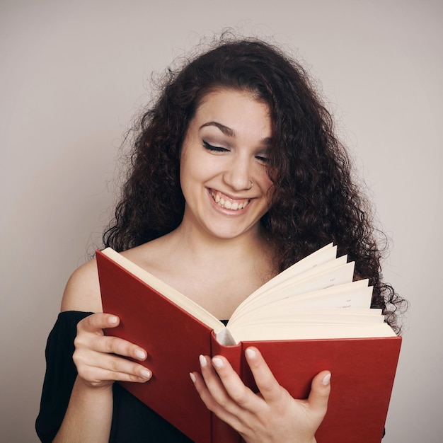 Donna sorridente che legge un libro contro il muro