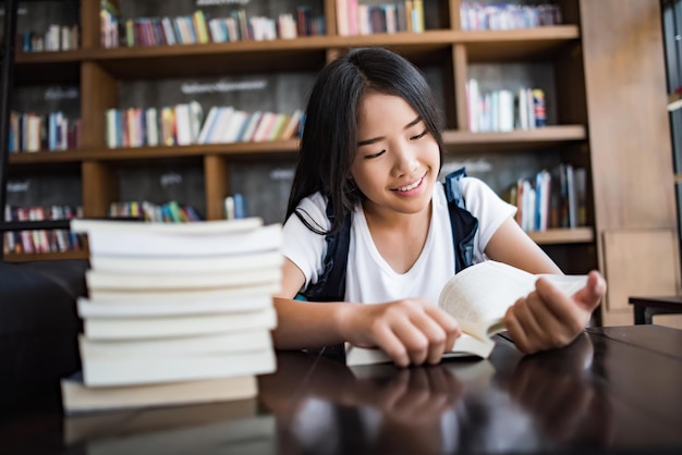 Donna sorridente che legge un libro mentre è seduta in un caffè