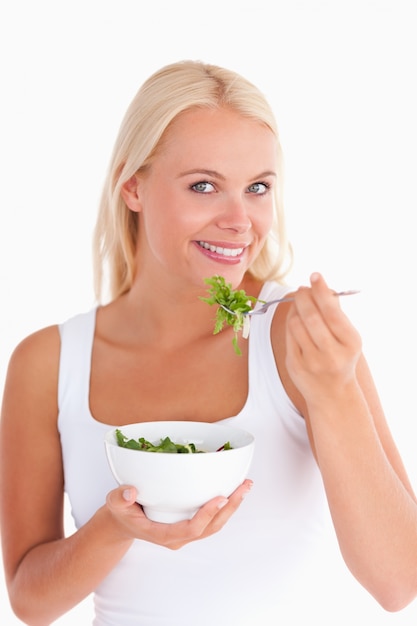 Donna sorridente che mangia insalata