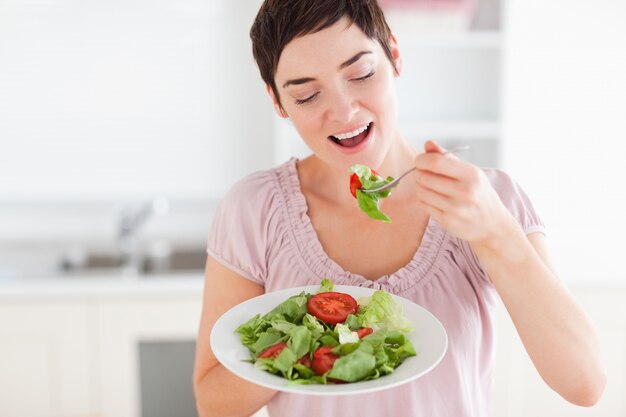 Donna sorridente che mangia insalata