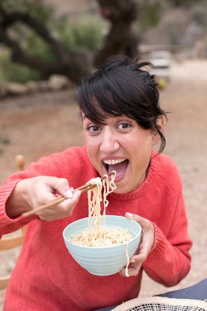 Donna sorridente che mangia tagliatelle colpo medio