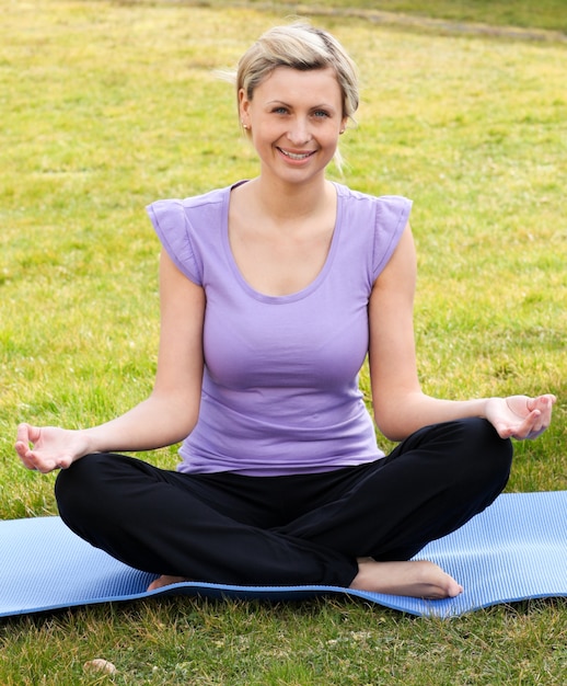 Donna sorridente che meditating seduta sull&#39;erba