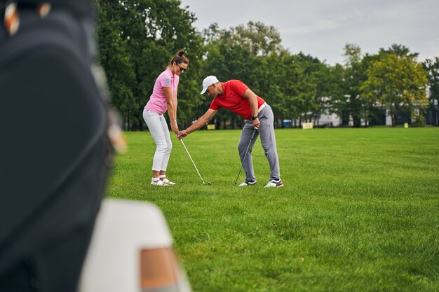 donna sorridente che pratica la corretta presa da golf assistita dal suo allenatore