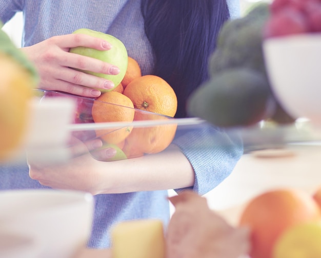 Donna sorridente che prende una frutta fresca dal concetto di cibo sano del frigorifero