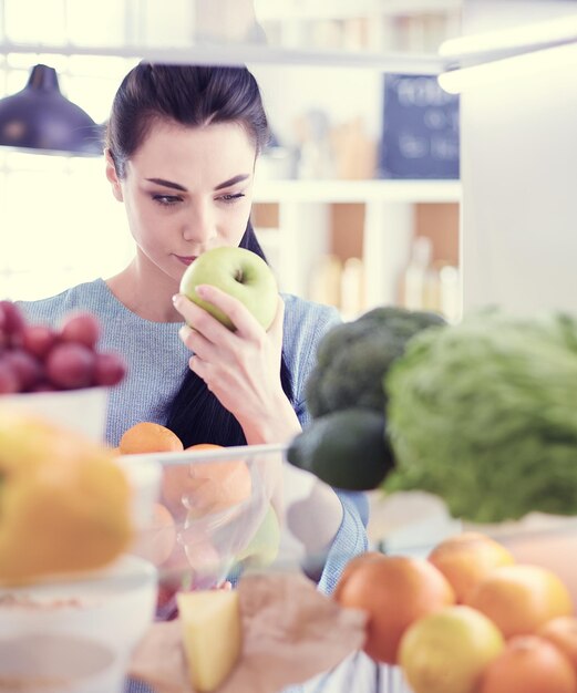 Donna sorridente che prende una frutta fresca dal concetto di cibo sano del frigorifero