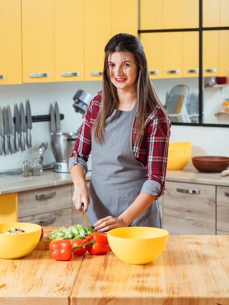 Donna sorridente che prepara le verdure nella cucina