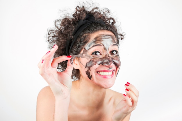 Donna sorridente che rimuove maschera purificante dal suo viso su sfondo bianco