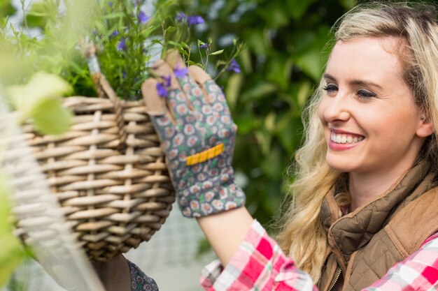 Donna sorridente che ripara un cestino di fiori d&#39;attaccatura