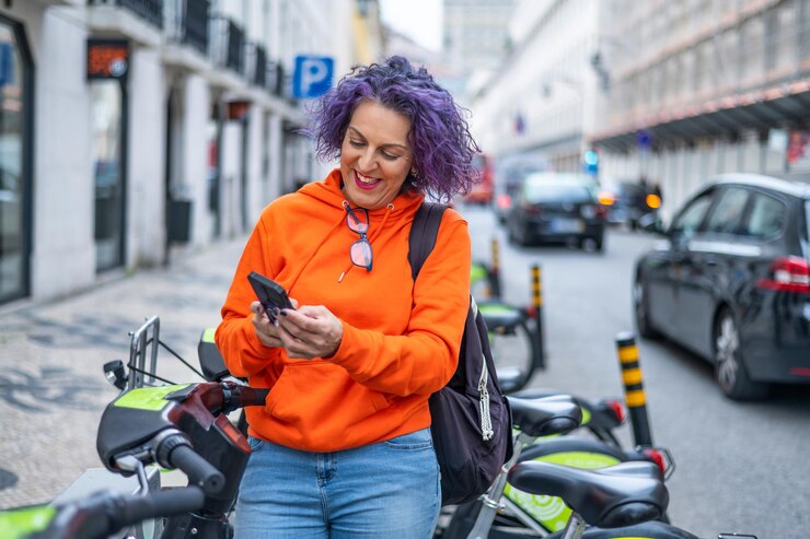 Foto donna sorridente che sblocca la bici elettrica tramite smartphone tecnologia ed ecocompatibilità