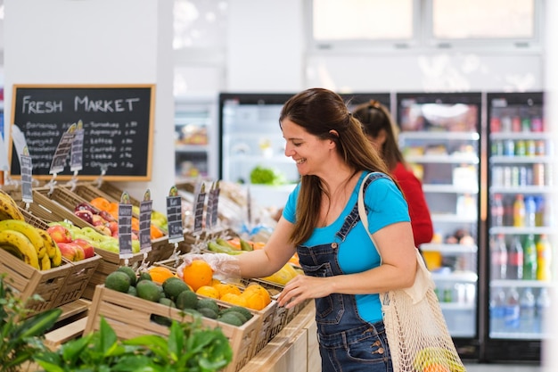 Donna sorridente che seleziona frutta al minimarket