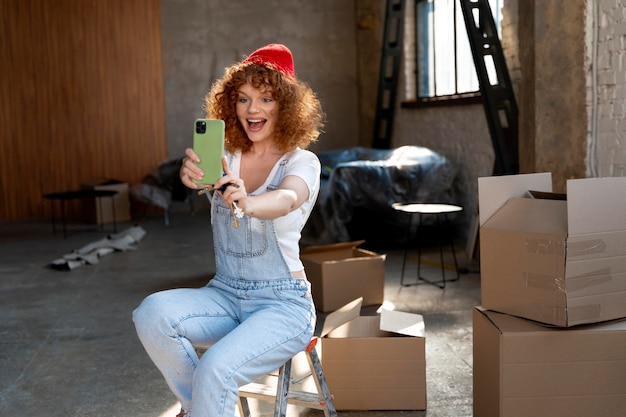 Donna sorridente che si fa selfie con lo smartphone nella sua nuova casa