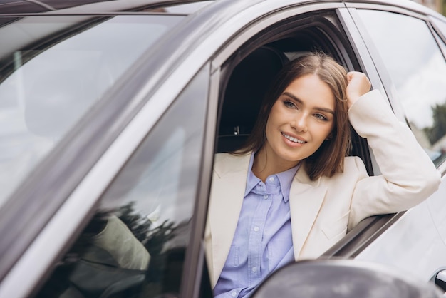 Donna sorridente che si rilassa alla finestra dell'auto in una giornata di sole