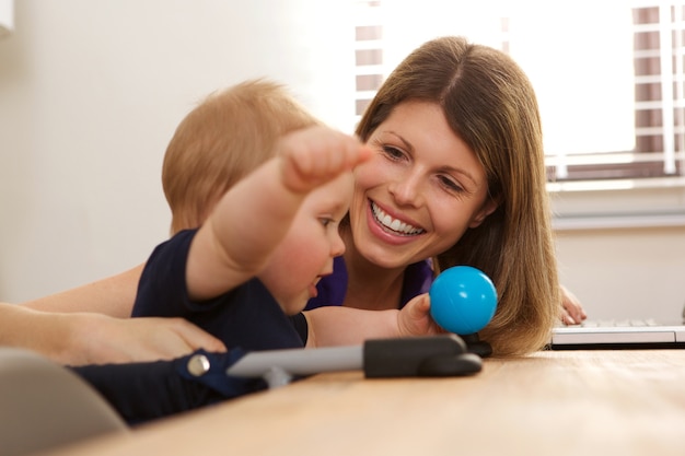 Donna sorridente che si siede al tavolo con il neonato