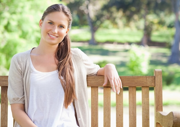 Donna sorridente che si siede su una panchina del parco