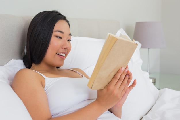 Donna sorridente che si trova sulla lettura del letto