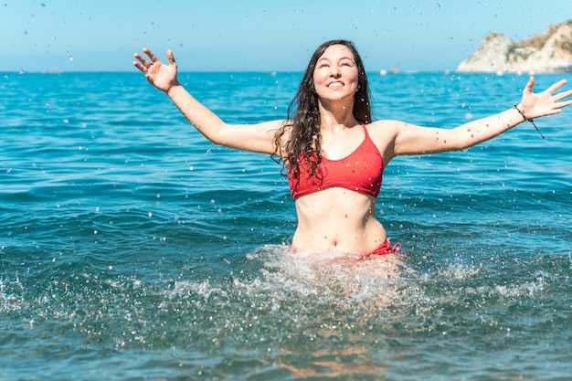 Donna sorridente che spruzza acqua nel mare