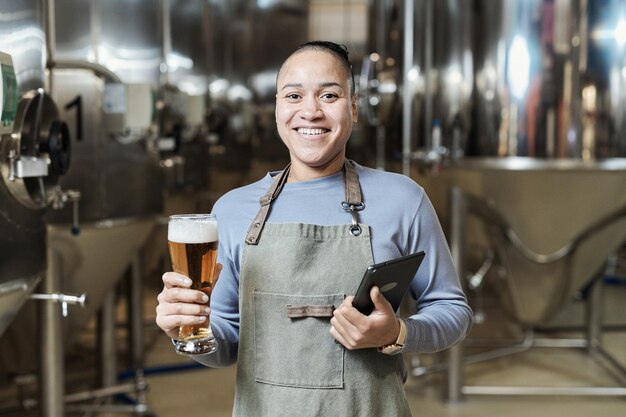 Donna sorridente che tiene il bicchiere di birra alla fabbrica di birra