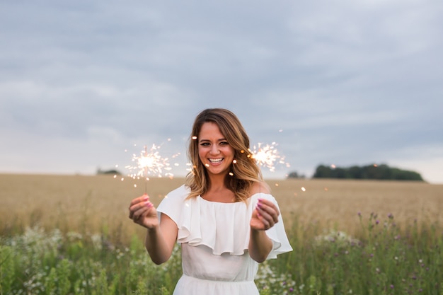 Donna sorridente che tiene sparkler e festeggia all'aperto