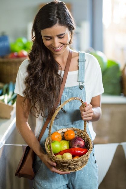 Donna sorridente che tiene un cesto di frutta