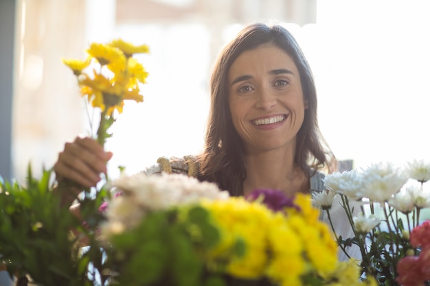 Donna sorridente che tiene un mazzo di fiori al negozio di fiori