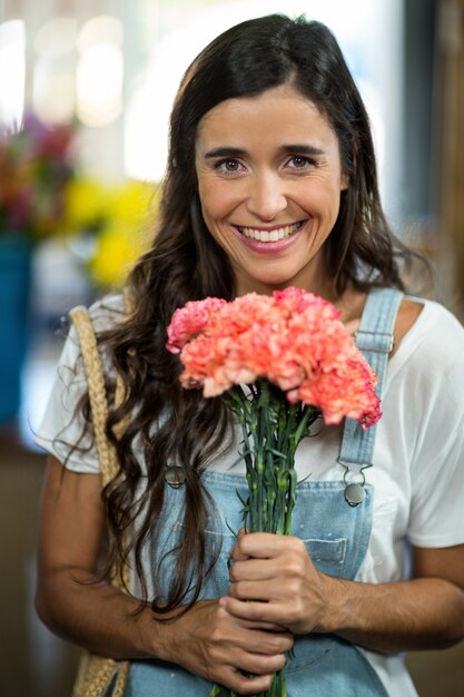 Donna sorridente che tiene un mazzo di fiori al negozio di fiori