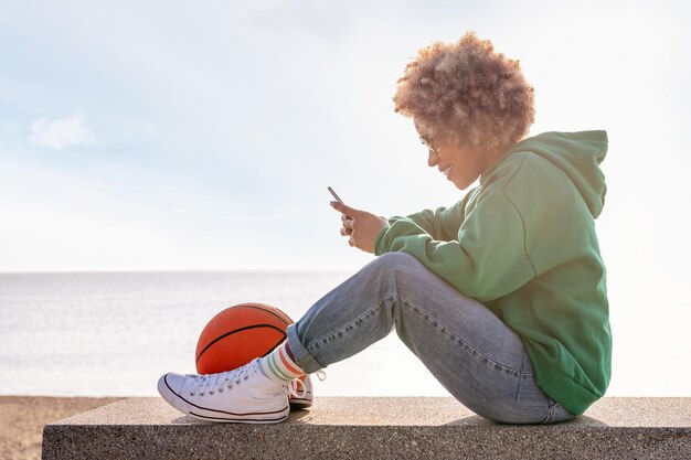 Donna sorridente che usa il suo telefono seduto su una panchina