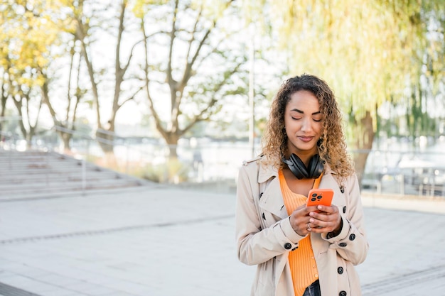 Donna sorridente che usa lo smartphone per strada