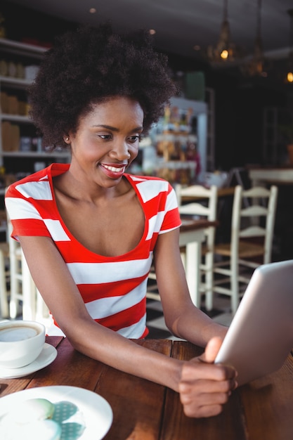 Donna sorridente che utilizza compressa digitale nel caffè