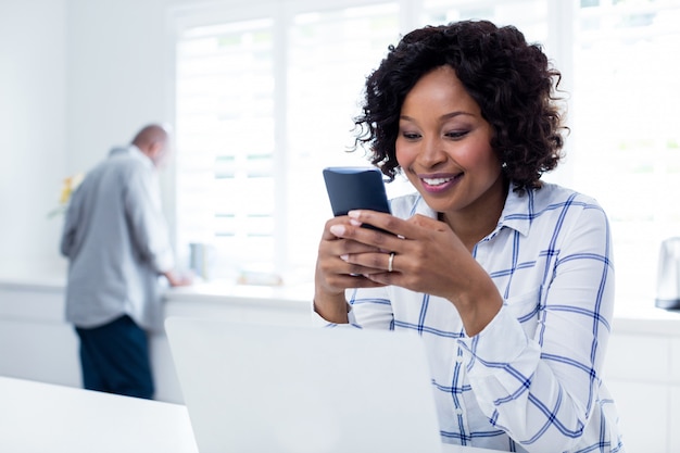 Donna sorridente che utilizza telefono cellulare nel salone