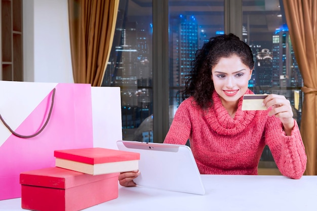 Donna sorridente che utilizza una carta di credito e un tablet