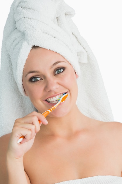 Donna sorridente con asciugamano per capelli lavarsi i denti