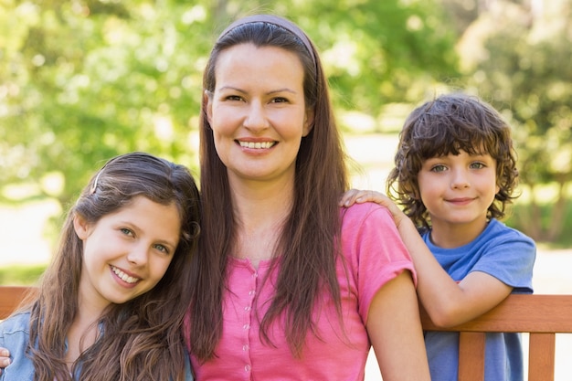 Donna sorridente con bambini seduti sulla panchina del parco